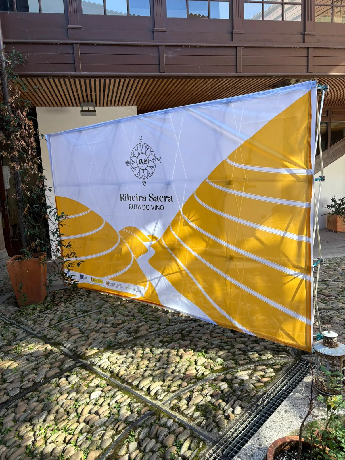 Photocall de la Ruta del Vino Ribeira Sacra con bancales en amarillo dorado y logotipo sobre fondo blanco